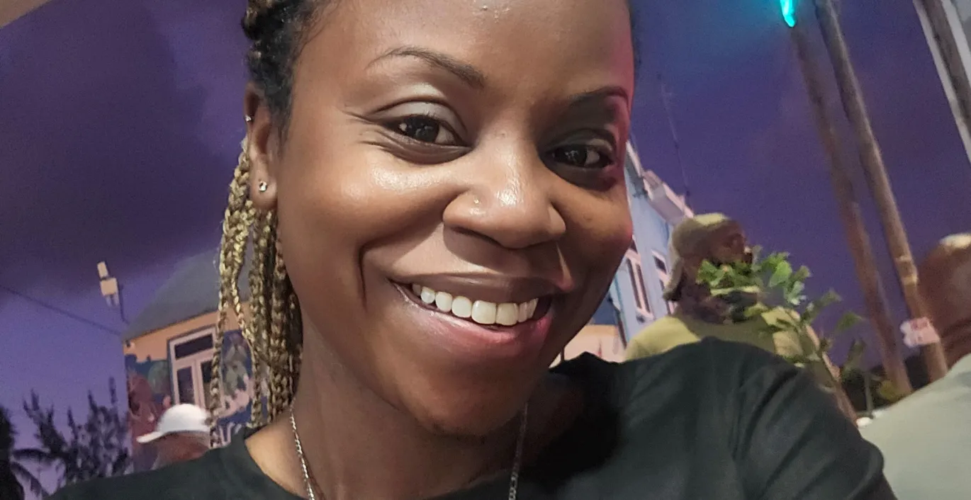 Janelle, wearing a black shirt, and hair in a ponytail.