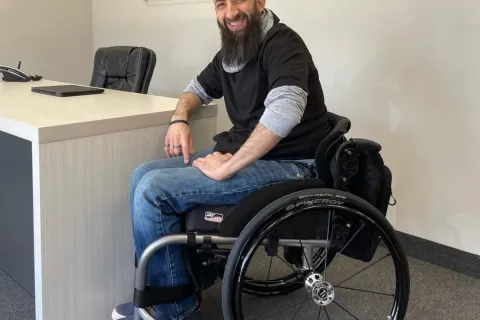 Terry, wearing a black shirt and blue jeans, sitting in a wheelchair.