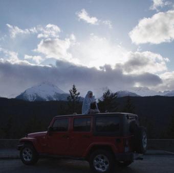 Imaan prays on top of her Jeep