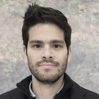 A headshot of MS researcher Dr. Carlos Camara-Lemarroy. He has short, dark hair and a short beard. He is smiling against a grey background.