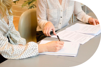 Two people sitting at a desk with paperwork.
