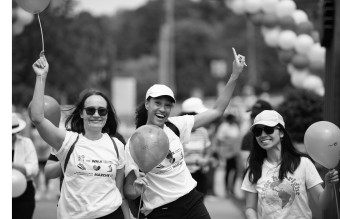 A group of volunteers holding baloons and cheering.