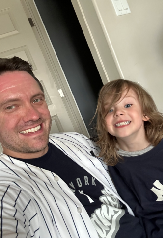 Brent, wearing a striped shirt, with his son, wearing a black shirt.