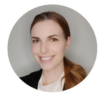 Smiling woman with auburn hair in a ponytail, wearing a dark blazer, circular crop portrait.