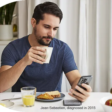 Man drinking coffee and browsing his phone at a breakfast table.