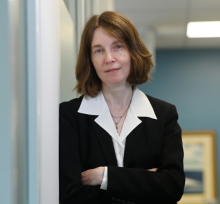 Professional woman with crossed arms, serious expression, in an office setting.