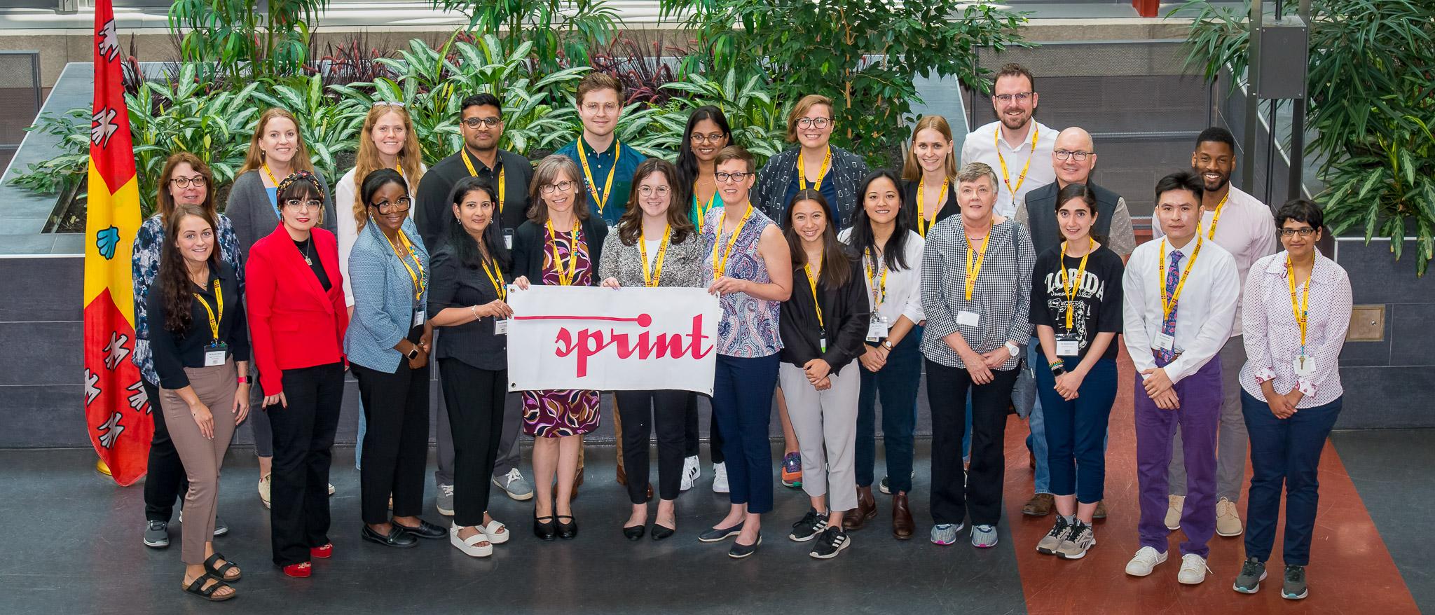 A group of people together holding a sign that says 'Sprint'