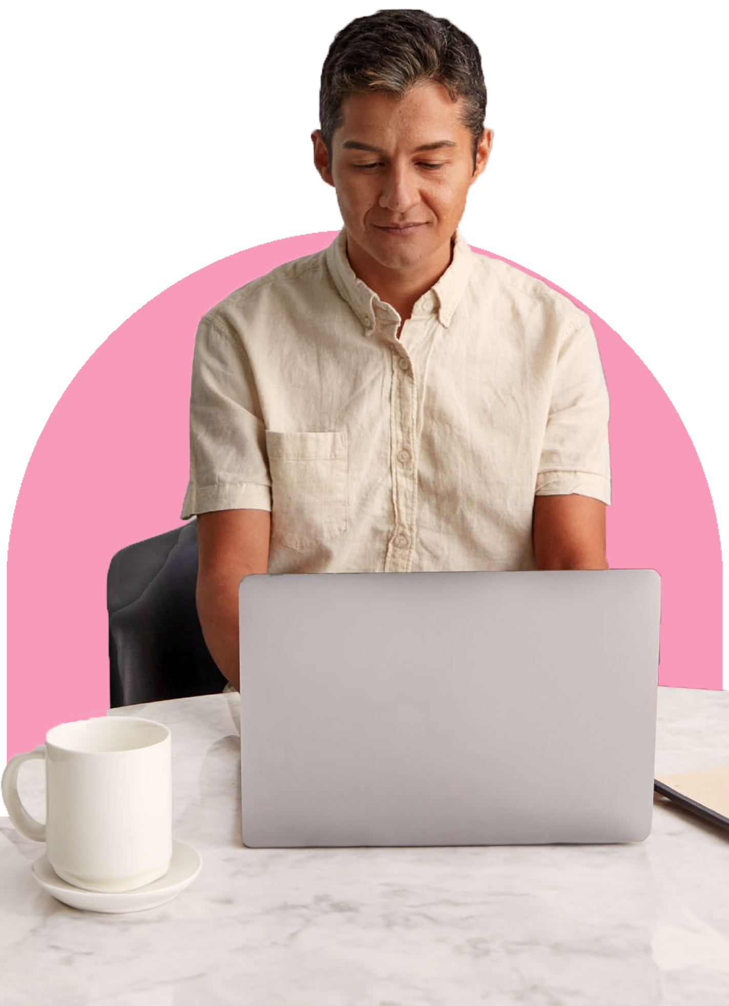 A man wearing a beige button up shirt sits and types on his laptop