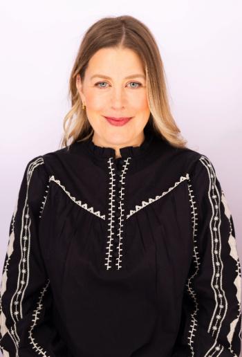 Julie-Anne Marceau, Directrice Générale de SP Canada - Montérégiennée. Elle porte un haut noir orné de motifs de couture blanc. Ses cheveux sont longs, blonds et lâchés, tombant sur ses épaules.
