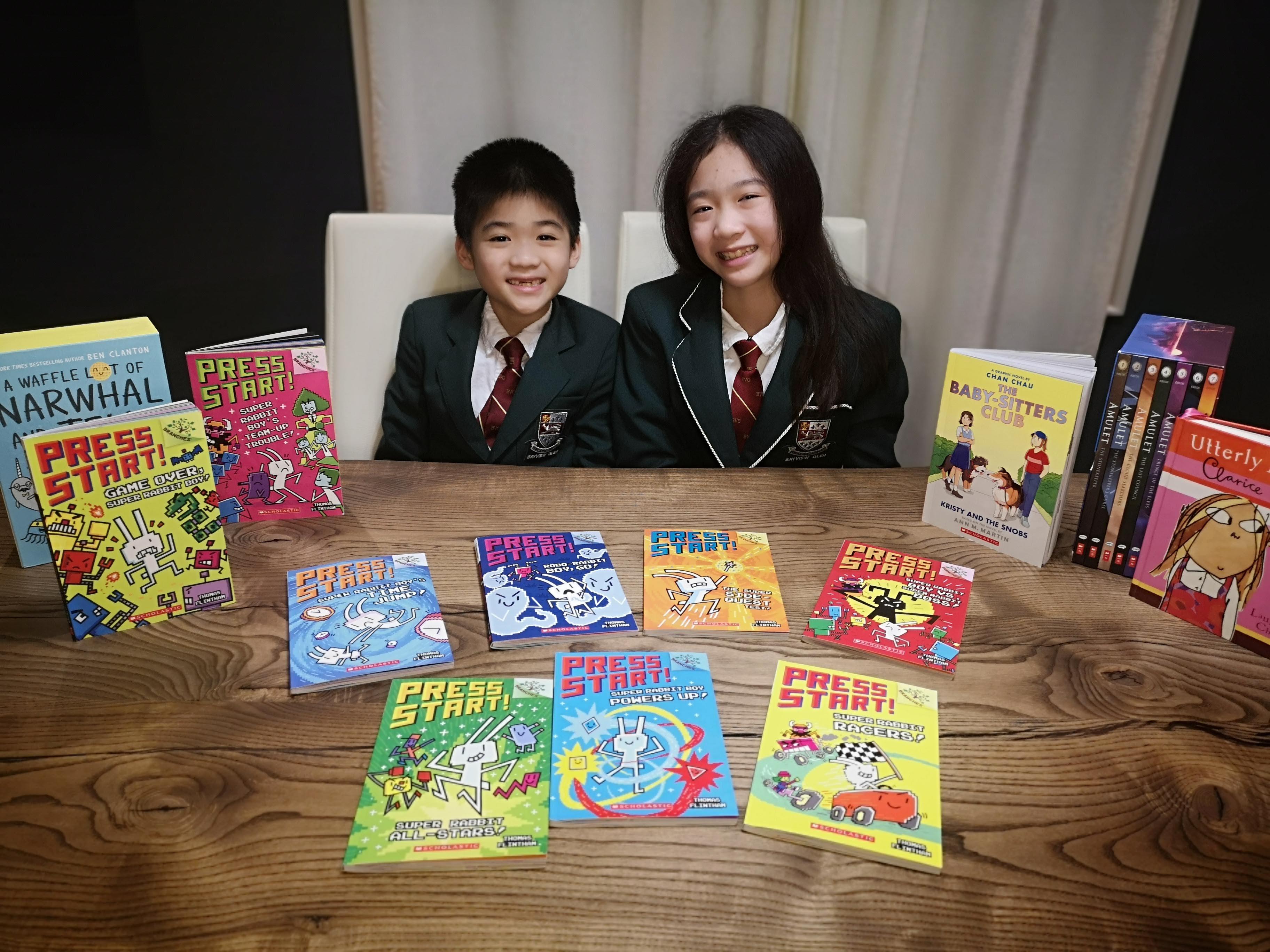 Erika and Kurtis, wearing a black uniform at a table, with books on it.