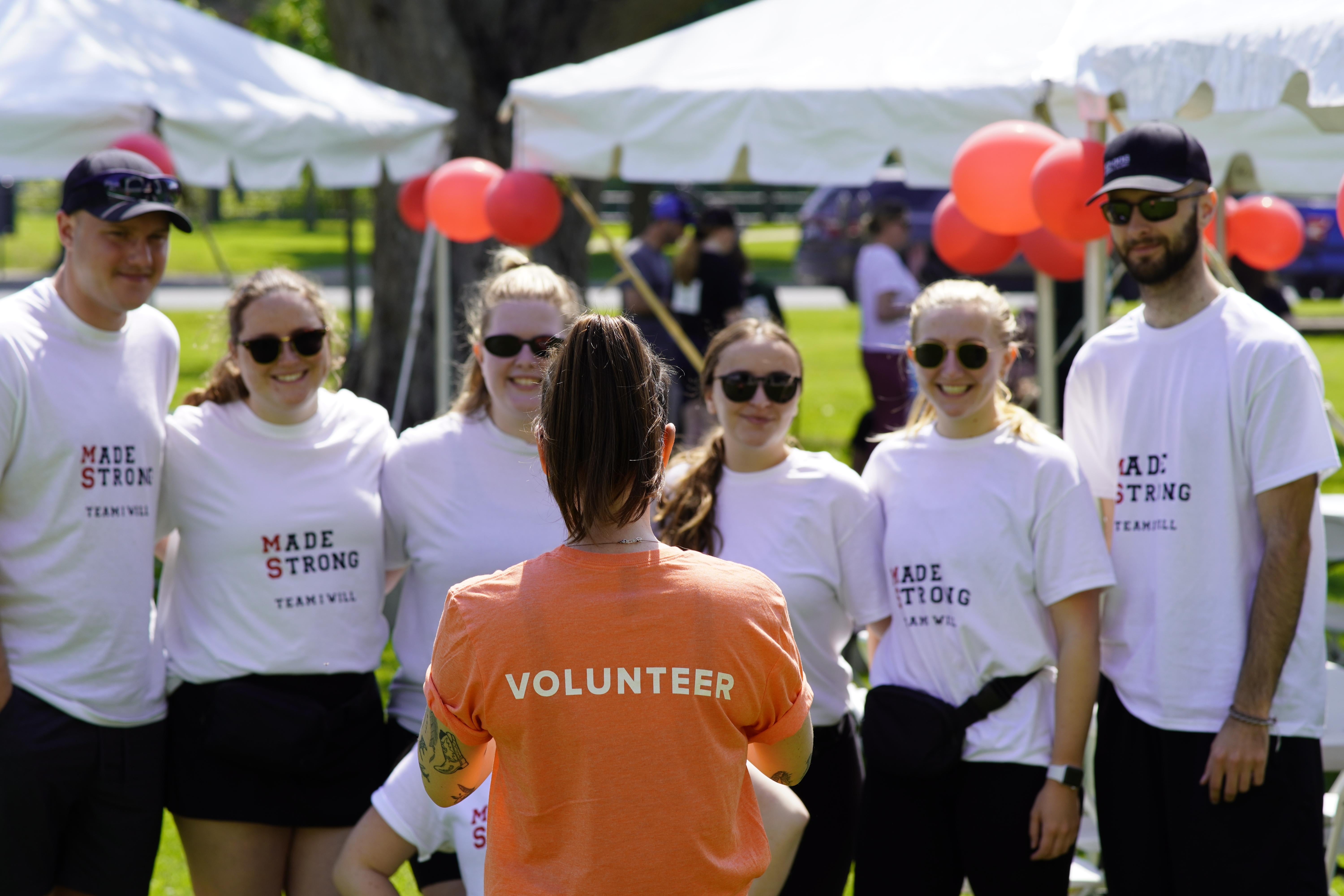 A woman with a brown ponytail is facing a small crowd of eager event participants.