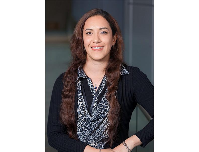 Dr. Rayatpour, wearing a black top, with long brown hair.