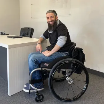 Terry, wearing a black shirt and blue jeans, sitting in a wheelchair.